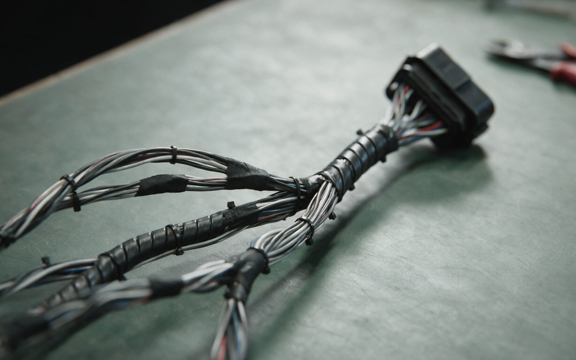 Illustration of a bundled wiring loom on a bench, breakouts taped and tied